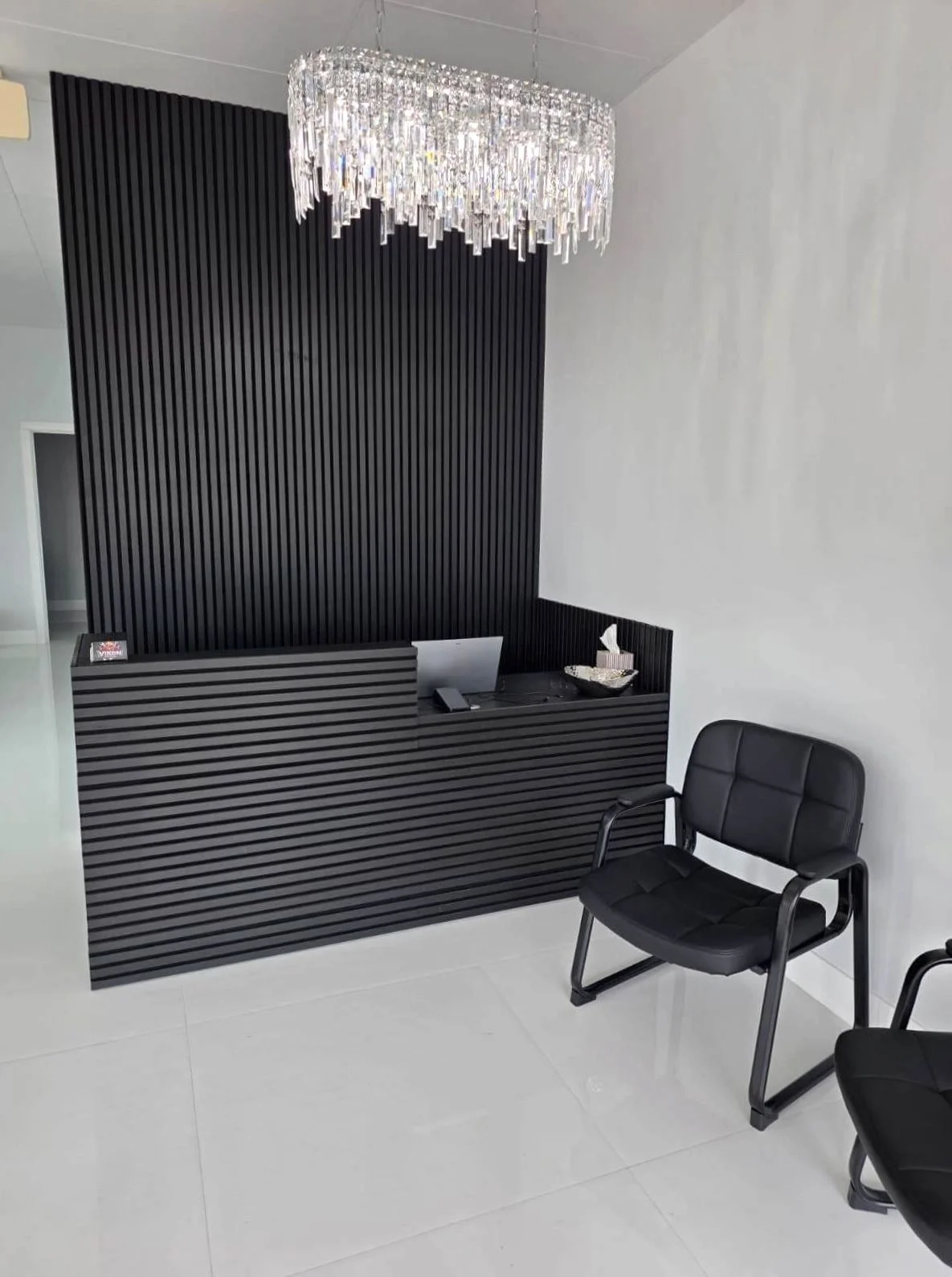 Black reception desk, chandelier and waiting chairs at Victoria Hair Club