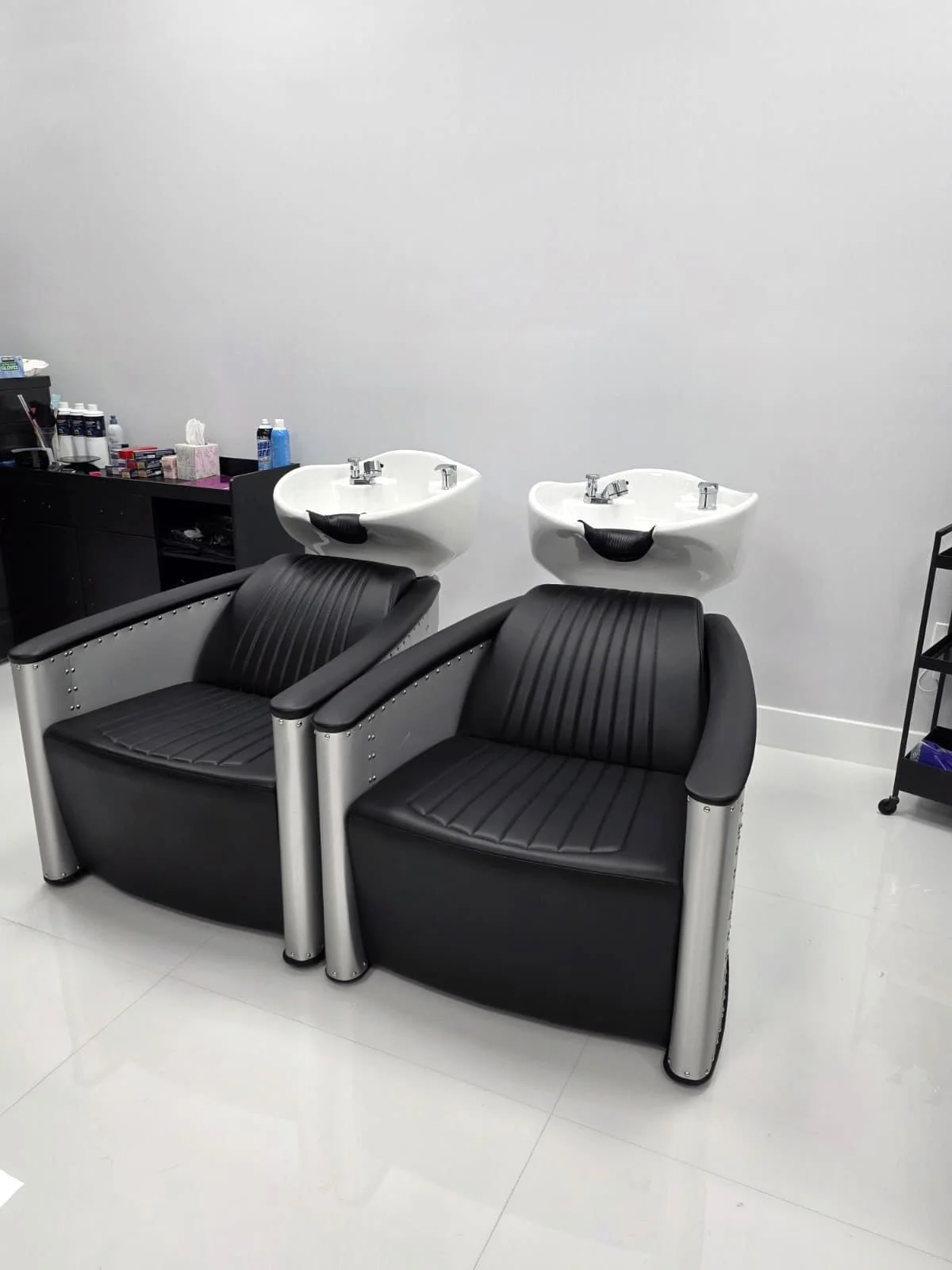 Two reclining shampoo chairs and white wash basins in the salon